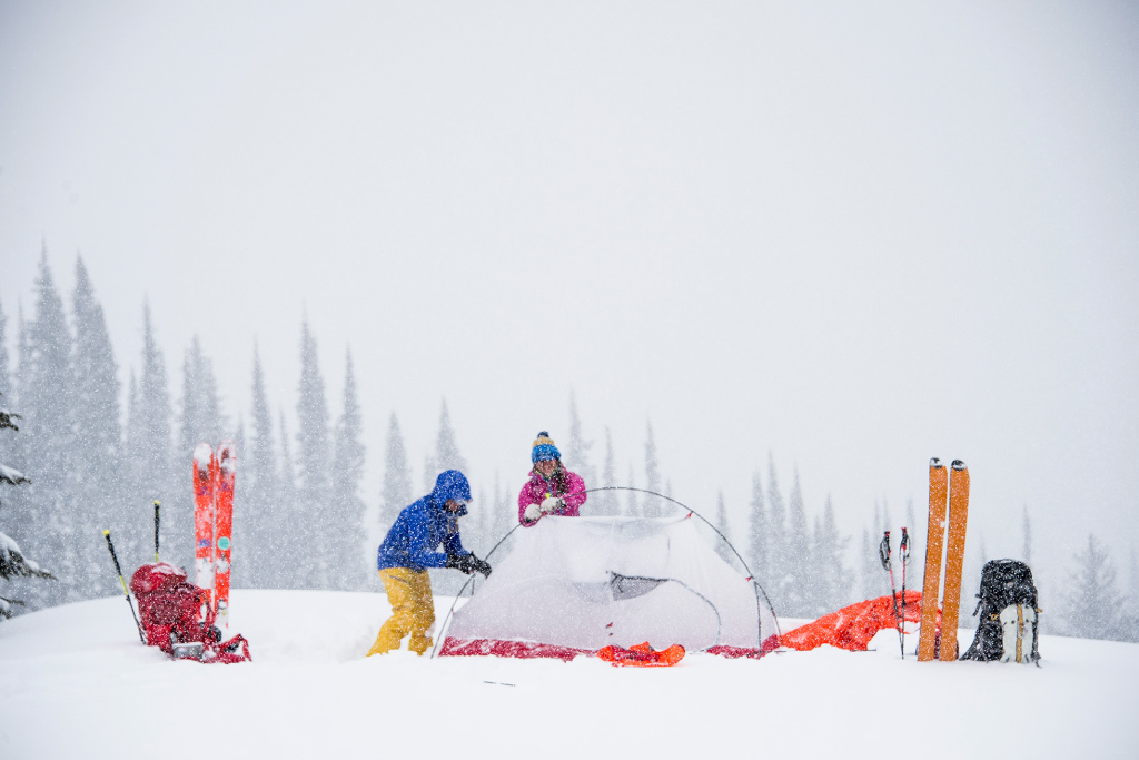 Skiers setting up tent in the snow