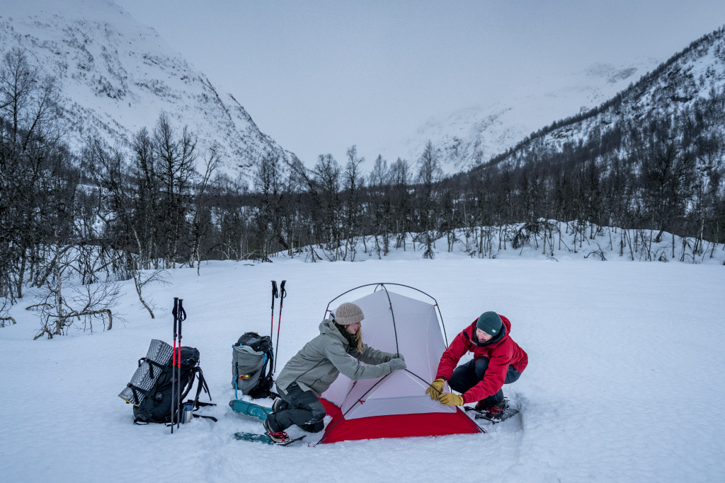 Snowshoers set up tent in snowy valley