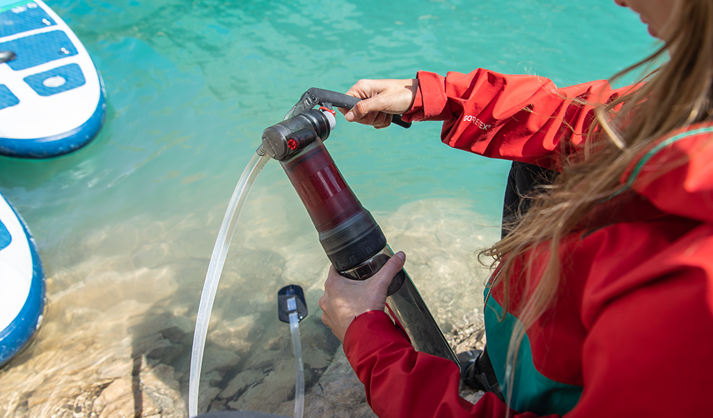 Woman pumping water through Guardian Purifier lakeside