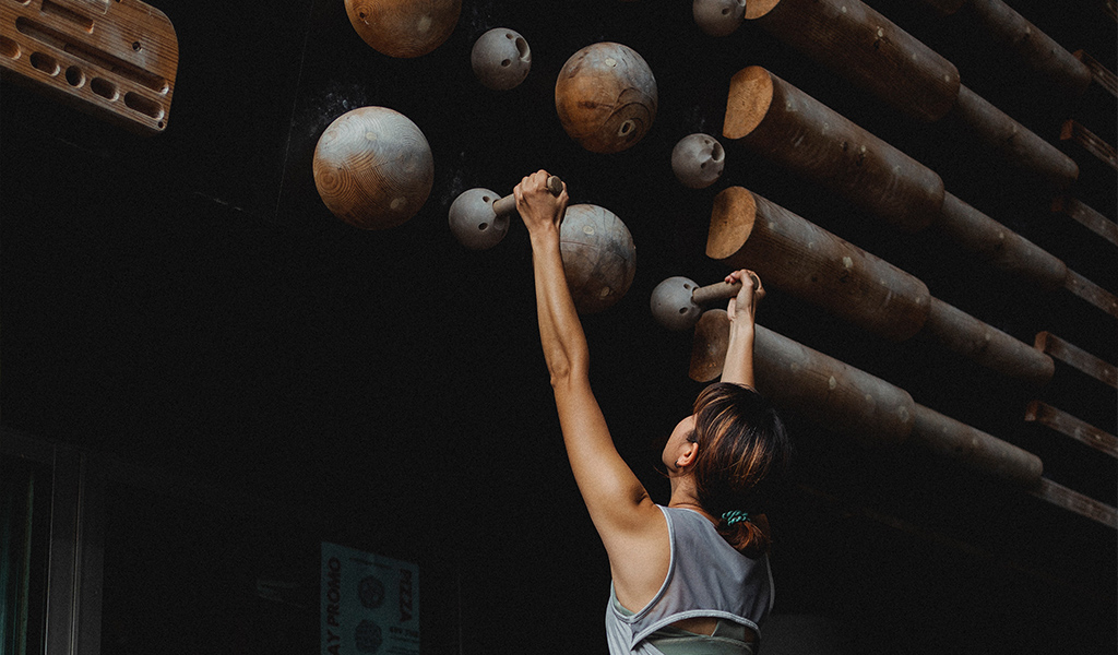 Woman in rock climbing gym hanging on peg board