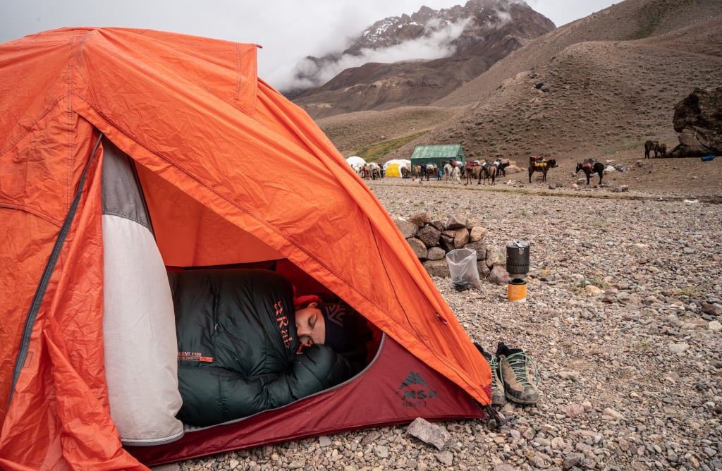 trekker sleeps in tent at camp