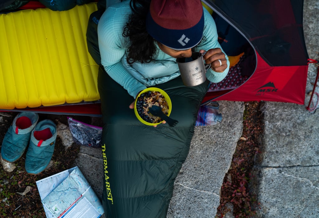 Backpacker eats meal while sitting in tent