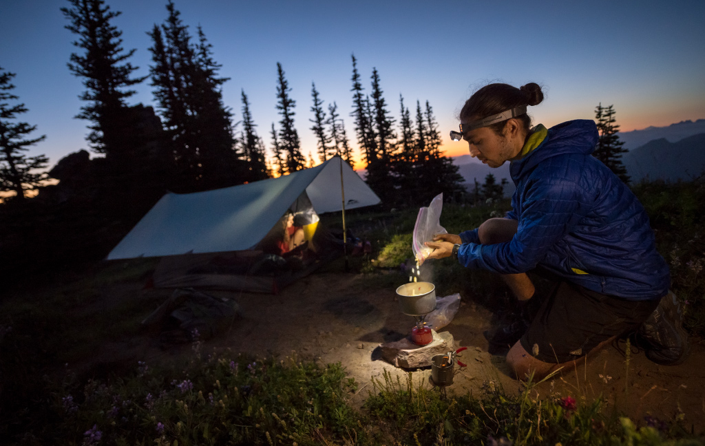 Thru-hiker cooking meal at sunset